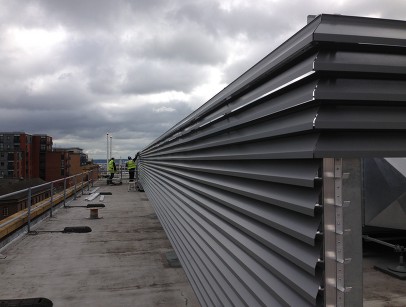 Men inspecting silver louvres on a rooftop